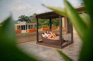 zwei Menschen sitzen in einem Pavillon auf einem Haus in der Unterkunft Hotel Natural Hill's by H&R in Villeta
