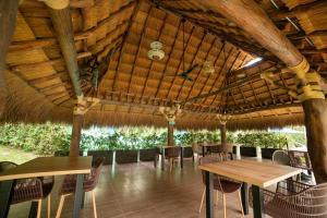 a restaurant with tables and chairs in a straw roof at Hotel Natural Hill's by H&R in Villeta