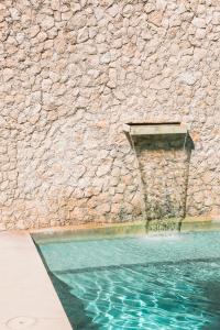 a swimming pool next to a stone wall at The Diplomat Boutique Hotel in Mérida