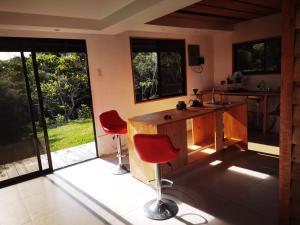 a kitchen with a counter and two red chairs at Casa Roble Cabaña romántica en la montaña de Costa Rica in San Cristóbal Sur