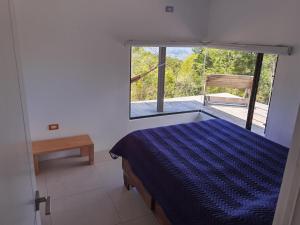 a bedroom with a blue bed and a window at Casa Roble Cabaña romántica en la montaña de Costa Rica in San Cristóbal Sur