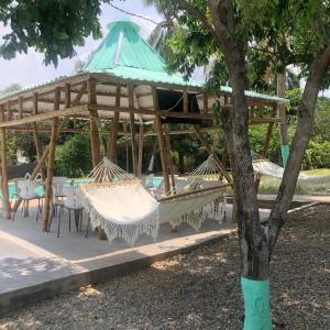 リカウルテにあるHotel Pallara Campestreのハンモックとテーブルと木が並ぶパビリオン