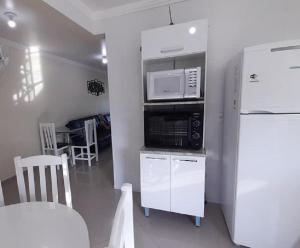 a kitchen with a white refrigerator and a microwave at Apto climatizado 502, apenas 5 min das Thermas in Piratuba