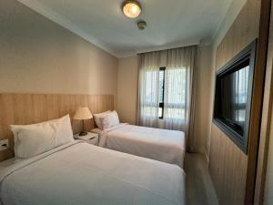 a hotel room with two beds and a window at Comfort Flat Pinheiros em Hotel 4,5 estrelas in Sao Paulo