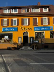 Gasthof Stern Asteri في Frickenhausen: مبنى برتقالي مع علامة على الجانب منه