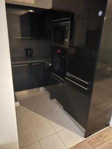 una cucina con frigorifero nero e pavimento piastrellato di Cosy appartement T3 meublé Aubervilliers - La Plaine ad Aubervilliers