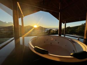 - une baignoire dans une chambre avec vue sur le coucher du soleil dans l'établissement Chalés Alto dos Pires, à São Bento do Sapucaí