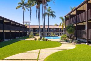 um pátio com palmeiras e uma piscina em Best Western Plus Pepper Tree Inn em Santa Bárbara