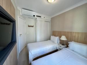 a hotel room with two beds and a television at Comfort Flat Pinheiros em Hotel 4,5 estrelas in Sao Paulo