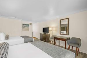 a hotel room with two beds and a desk and a television at Best Western Park Crest Inn in Monterey