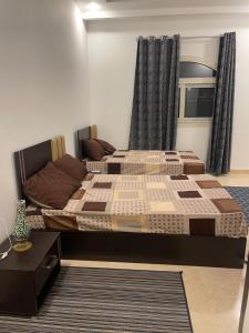 a bedroom with two beds and a table and curtains at Neama town in Sharm El Sheikh