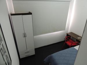a small room with a bed and a cabinet and a desk at room itaim in Sao Paulo