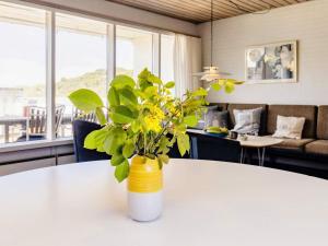 a yellow and white vase with a plant on a table at 6 person holiday home in Pandrup in Rødhus