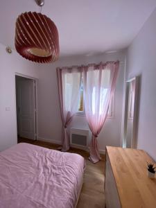 1 dormitorio con cortinas rosas, 1 cama y 1 mesa en Appartement charmant hypercentre, en Orléans