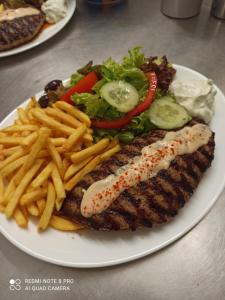 a plate of food with french fries and fish and a salad at Gasthof Stern Asteri in Frickenhausen