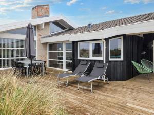 a deck with chairs and an umbrella on a house at Luxury Retreat with Sea View - By Traum Ferienwohnungen in Hjørring