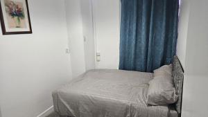 un piccolo letto in una camera con tenda blu di Luxury 2 bedrooms flat Leytonstone a Londra