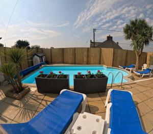uma piscina com duas cadeiras reclináveis azuis e plantas em Family Bungalow with Private Pool em Kilgetty