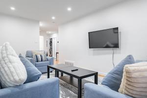 a living room with blue couches and a tv at Littlewood Properties in Toronto