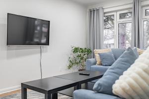 - un salon avec deux canapés bleus et une télévision dans l'établissement Littlewood Properties, à Toronto