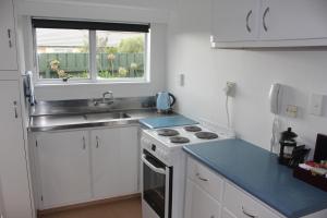 a kitchen with a sink and a stove and a window at Kapiti Gateway Motel in Waikanae