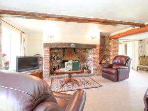 a living room with a couch and a fireplace at Lyons Green in Great Fransham
