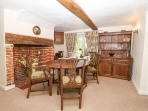 a dining room with a table and chairs and a fireplace at Lyons Green in Great Fransham