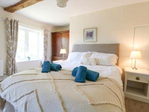 a bedroom with a large bed with blue pillows on it at Lyons Green in Great Fransham