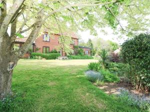 a house with a yard with a tree and flowers at Lyons Green in Great Fransham