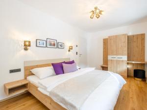 - une chambre avec un grand lit blanc et des oreillers violets dans l'établissement Roßbrand und Tauern-Blick, à Untertauern