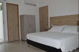 1 dormitorio con 1 cama blanca grande y armarios de madera en Hotel Ranchería Campestre, en Sahagún