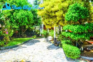 un jardín con árboles y una pasarela de piedra en Castle Bay Resort, en Weligama