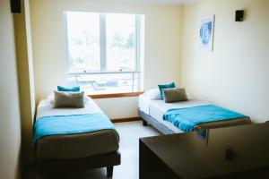 Cette petite chambre comprend 2 lits et une fenêtre. dans l'établissement Apart Hotel Aragon Portal, à Temuco