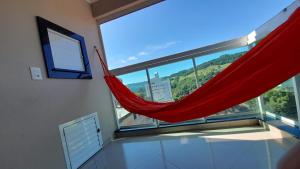 een rode hangmat in een kamer met een groot raam bij Apto climatizado 502, apenas 5 min das Thermas in Piratuba
