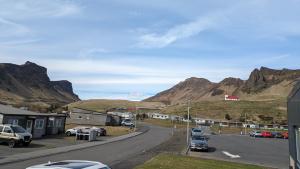 a street with cars parked on the side of a mountain at Black Beach Apartment - Vík in Vík +2 photos