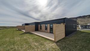 a modern house on a grassy field with a building at Black Beach Apartment - Vík in Vík
