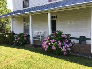 eine Veranda eines Hauses mit einer Bank und Blumen in der Unterkunft Historic 1850s Home at the Base of Jump Mountain Near Lexington in Goshen