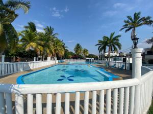 a swimming pool with a white fence and palm trees at CASA VACACIONAL SAMARIA in Flandes