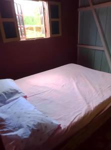 un letto con lenzuola bianche in una stanza con finestra di Casas Salomão a Santo António