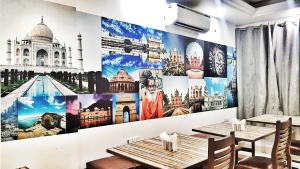 Airport Hotel Delhi Aerocity في نيودلهي: مطعم بطاولتين وجدار جداري للمعالم السياحية