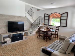 a living room with a tv and a table with chairs at Casa Colonial Recanto da Família & Amigos e Kit Anexa! in São Pedro da Aldeia