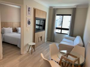 um quarto de hotel com uma cama, uma mesa e cadeiras em Comfort Flat Pinheiros em Hotel 4,5 estrelas em São Paulo