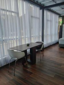 uma mesa e cadeiras num quarto com janelas em El Castillo em Bogotá