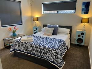 a bedroom with a bed with a blue and white comforter at Bowen Sunrise Retreat Homestay in Bowen