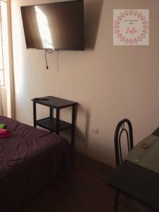 a room with a bed and a table and a television at La casita de Lulú in Arequipa