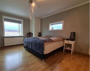 um quarto com uma cama grande e 2 janelas em Ibúð með einstöku útsýni em Sauðárkrókur