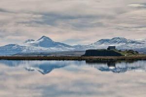 un reflejo de montañas cubiertas de nieve en un cuerpo de agua en Ibúð með einstöku útsýni en Sauðárkrókur