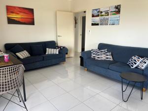 een woonkamer met twee blauwe banken en een tafel bij Bowen Sunrise Retreat Homestay in Bowen