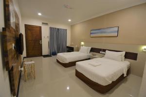 a hotel room with two beds and a television at Hemingway Cottage 海明威度假屋 in Semporna