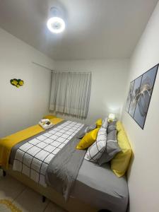 una camera da letto con un grande letto con cuscini gialli di Maria Apê São Mateus l Garagem l WiFi l Térreo l Um minuto do shopping independência a Juiz de Fora